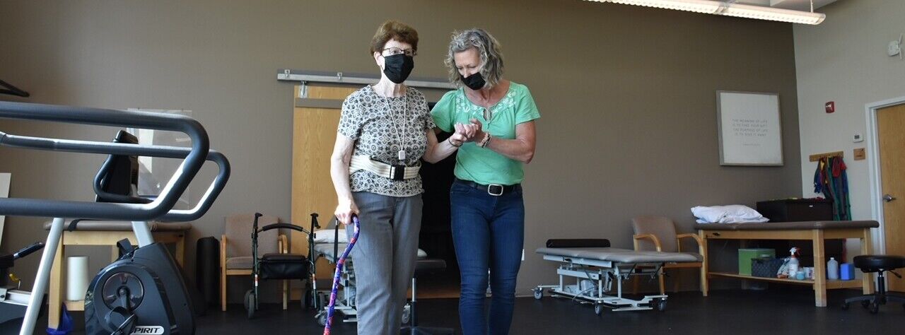 A physical therapist and a patient walk in the clinic